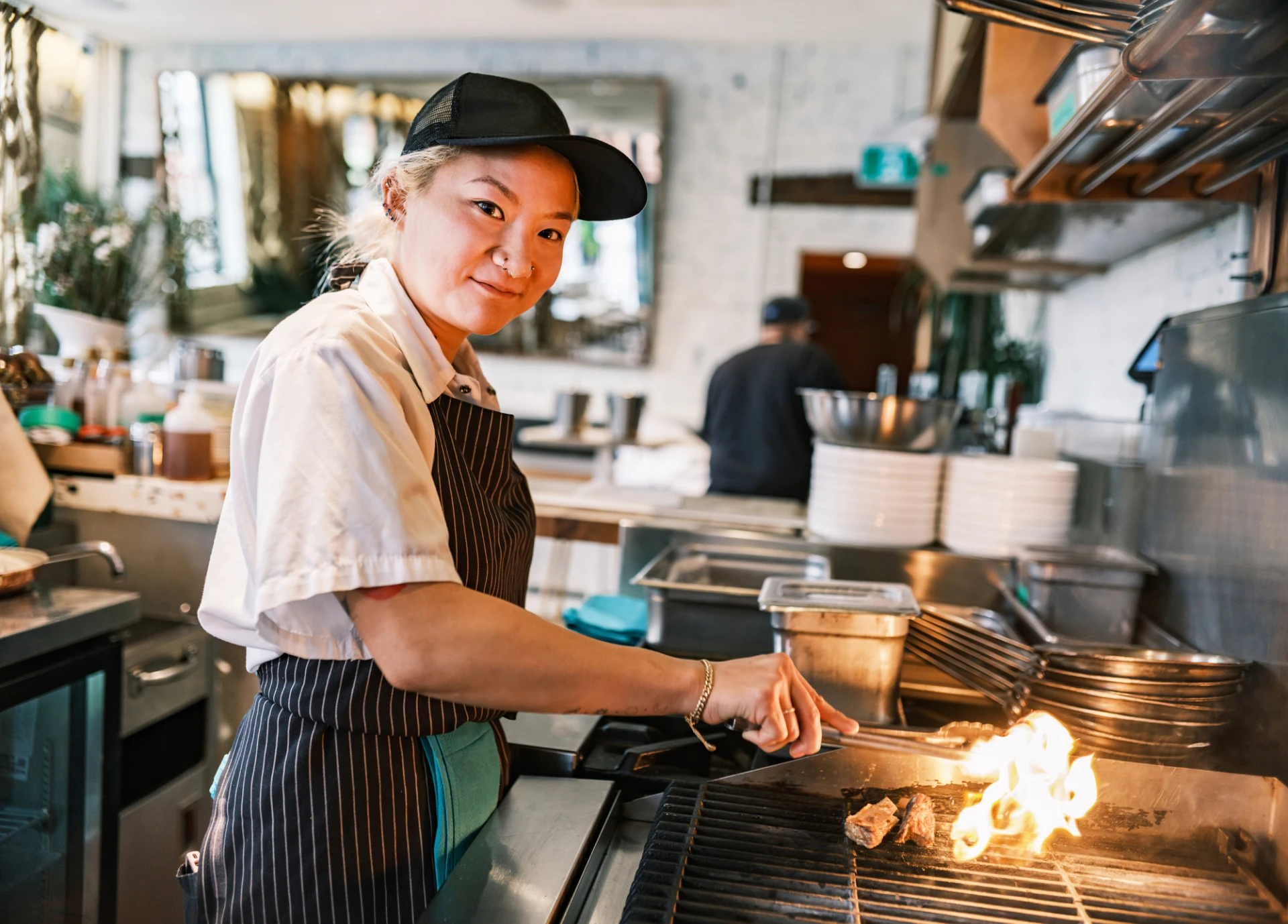 Chef grilling food in a restaurant kitchen.